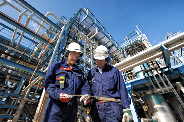 Two Oil and Gas Workers in front of Combined Cycle Plant piping